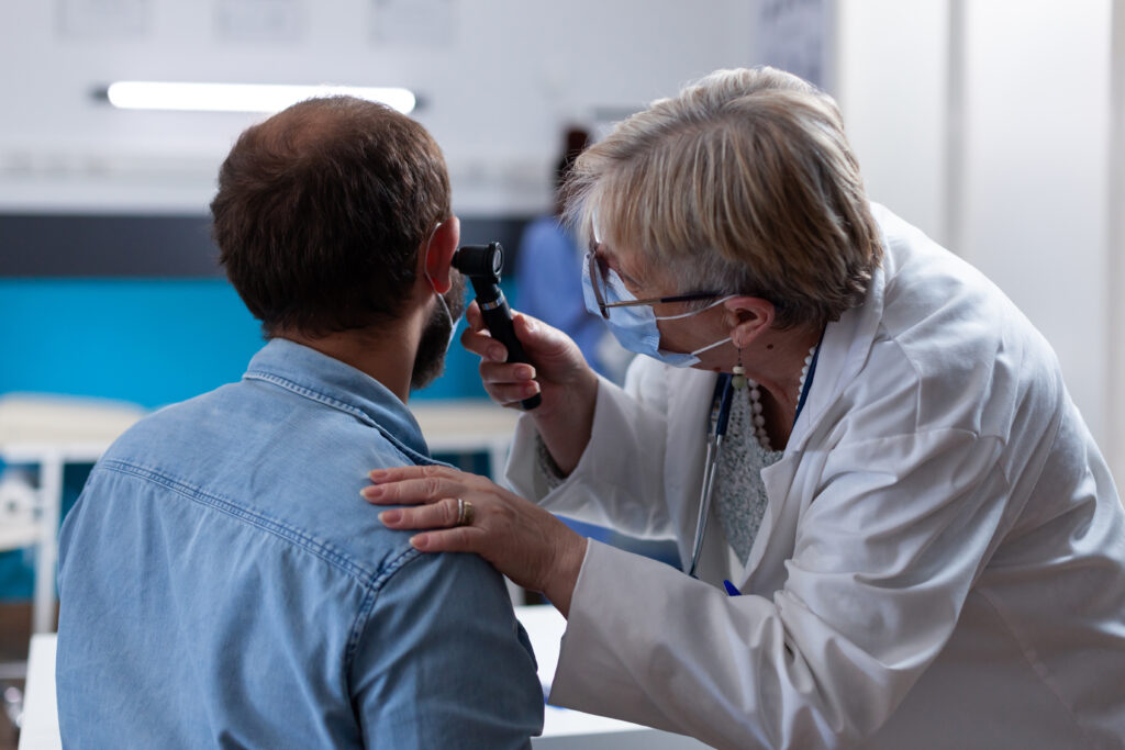 Close up of physician using otoscope to do ear consultation with patient